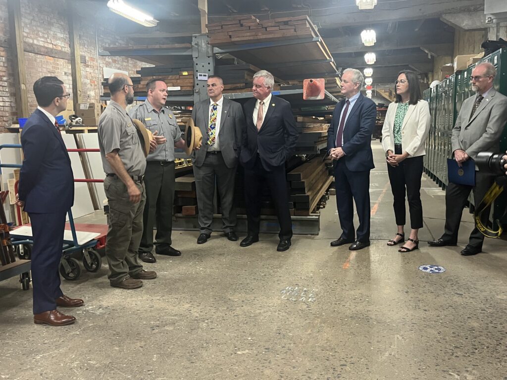 NPS workers talk to a group of people talking in large workshop area.