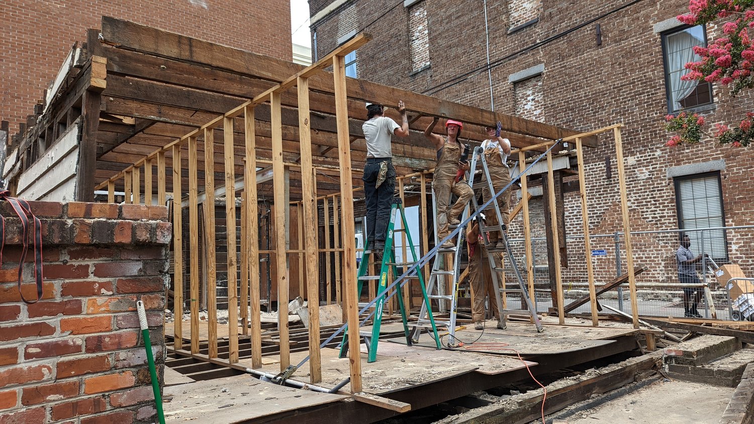 Two men at a window with a power tool